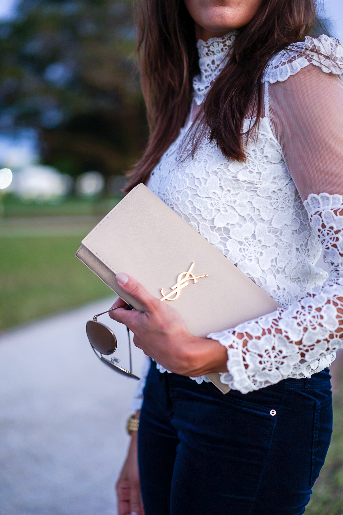 A Glam Lifestyle blogger carrying YSL monogram clutch in a lace blouse