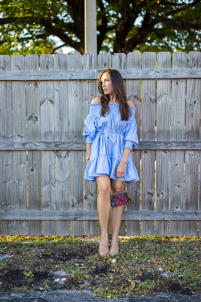 A Glam Lifestyle Blogger Amanda Champio leanign on a wall and wearing blue dress