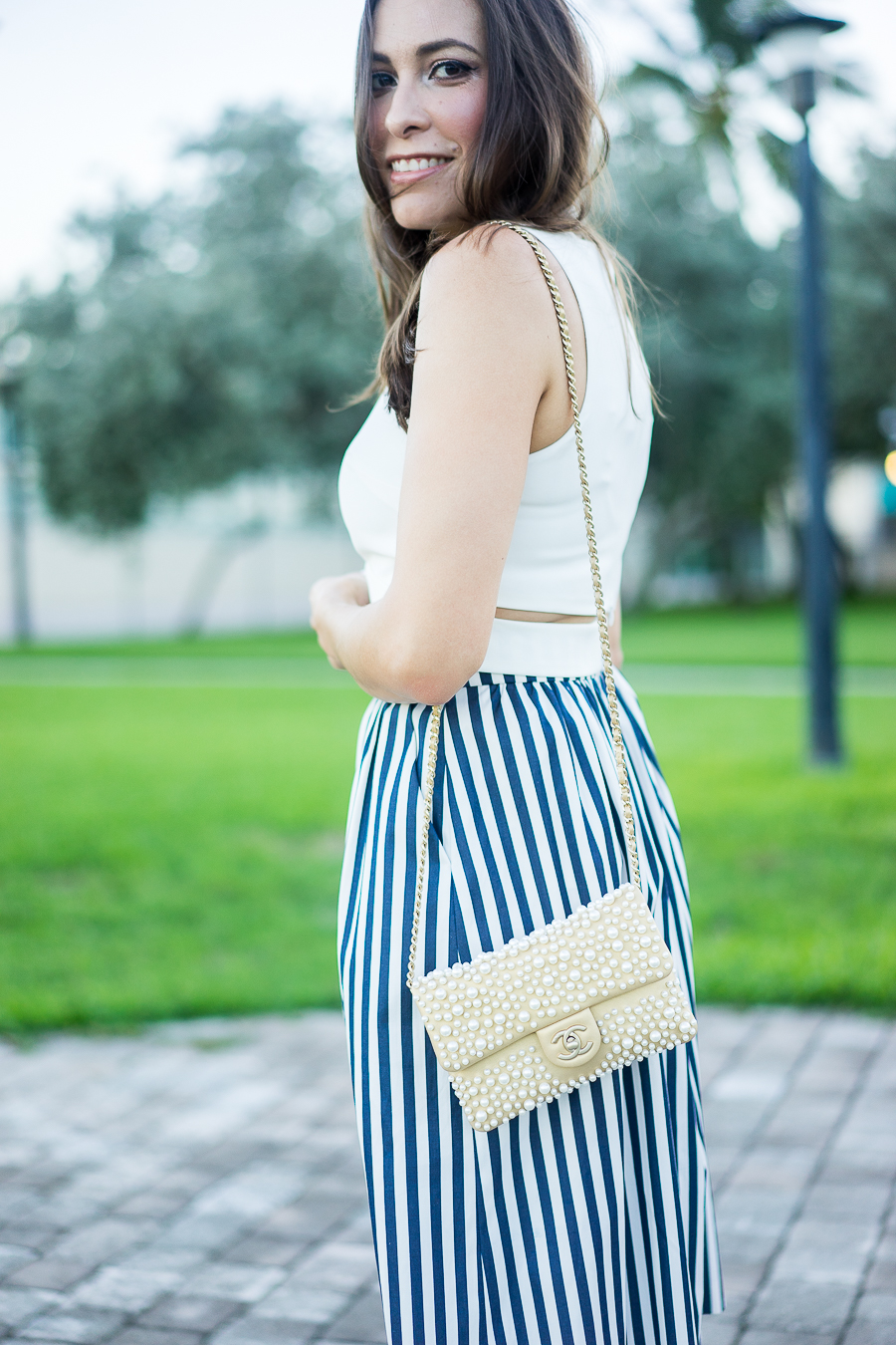 White crop top, striped skirt, Chanel pearl bag