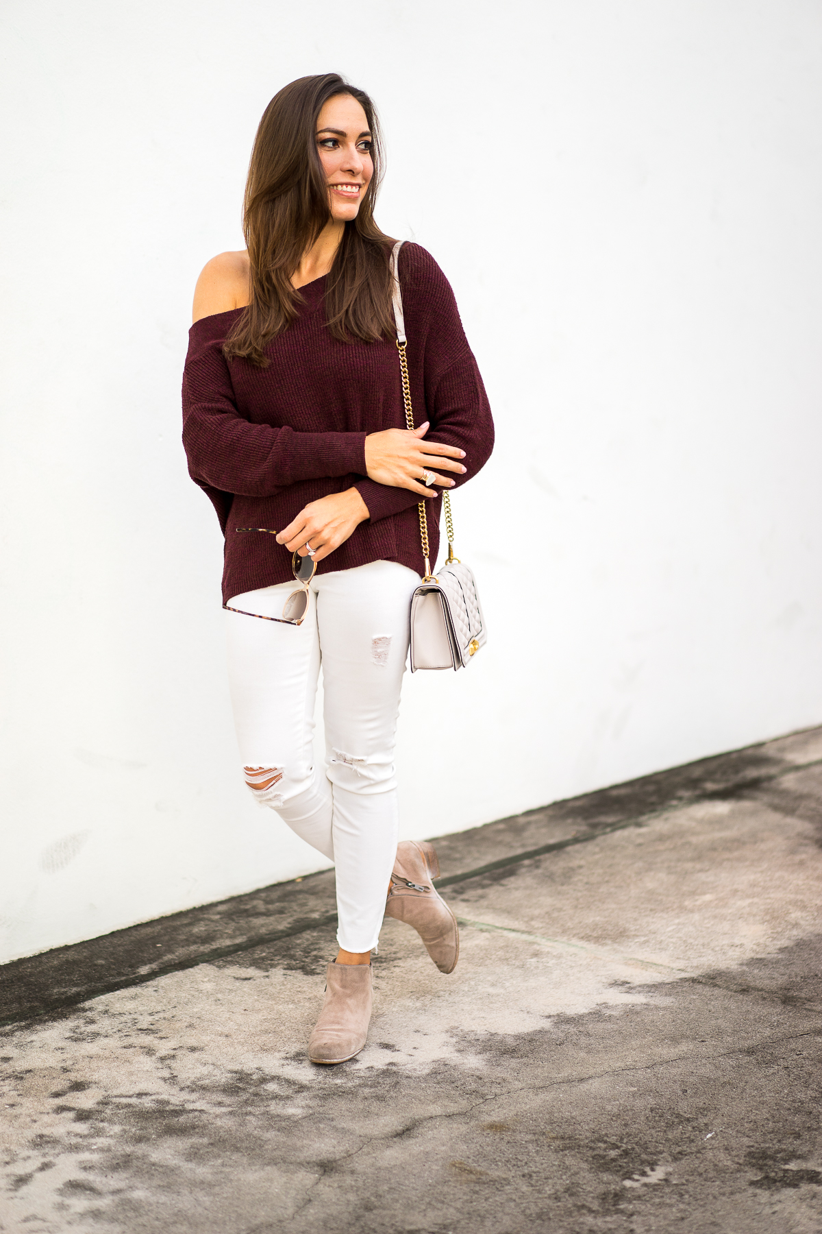 A Glam Lifestyle blogger Amanda Mercado wearing Free People burgundy off the shoulder sweater with white distressed denim and ankle booties