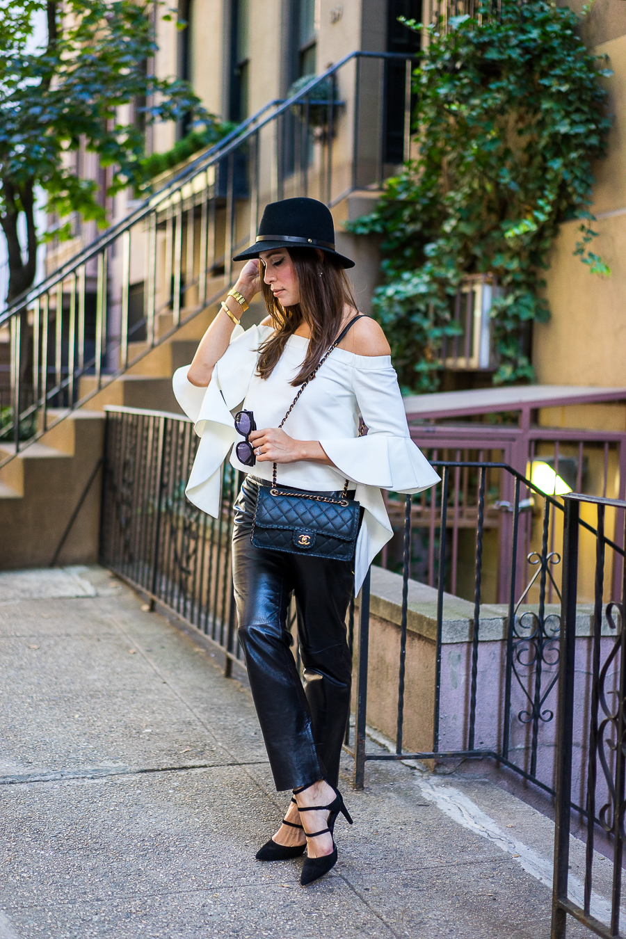 A Glam Lifestyle blogger wearing chicwish white off-the-shoulder top with milly black leather cropped pants and classic chanel bag with a rag and bone fedora and strappy-black-sandals