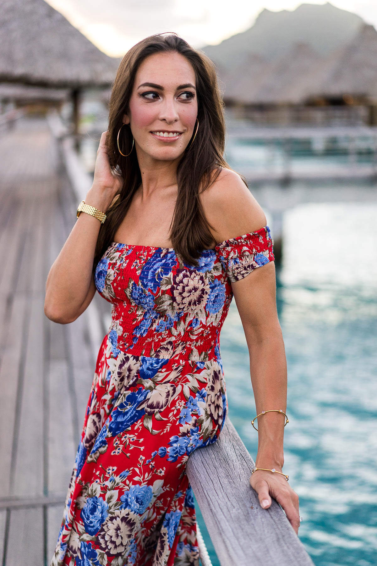 A Glam Lifestyle fashion blogger watches sunset in Bora Bora wearing Auguste the Label floral maxi dress and tan bow sandals with gold jewelry