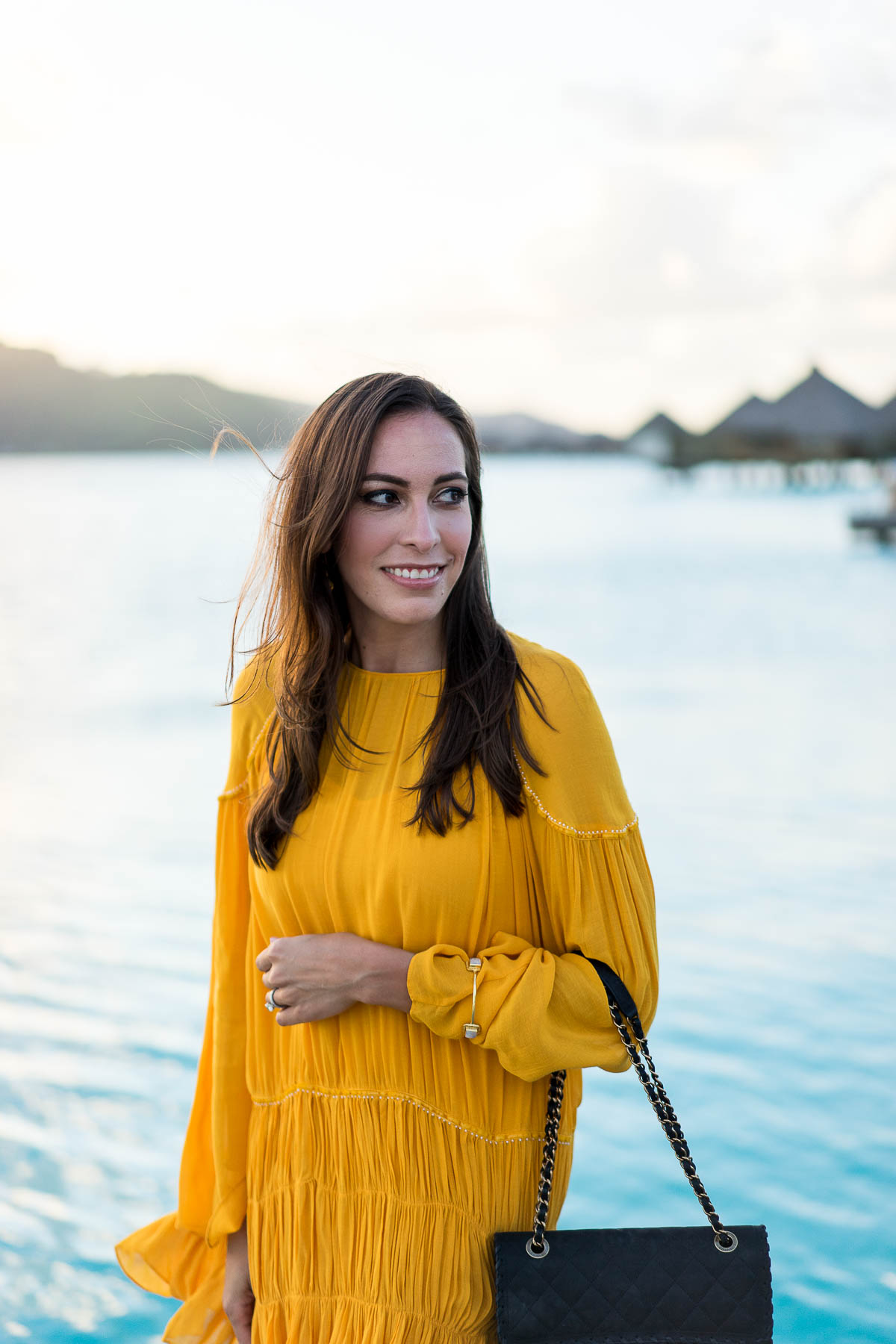 Amanda from A Glam Lifestyle wears mustard yellow dress and classic Chanel bag on honeymoon
