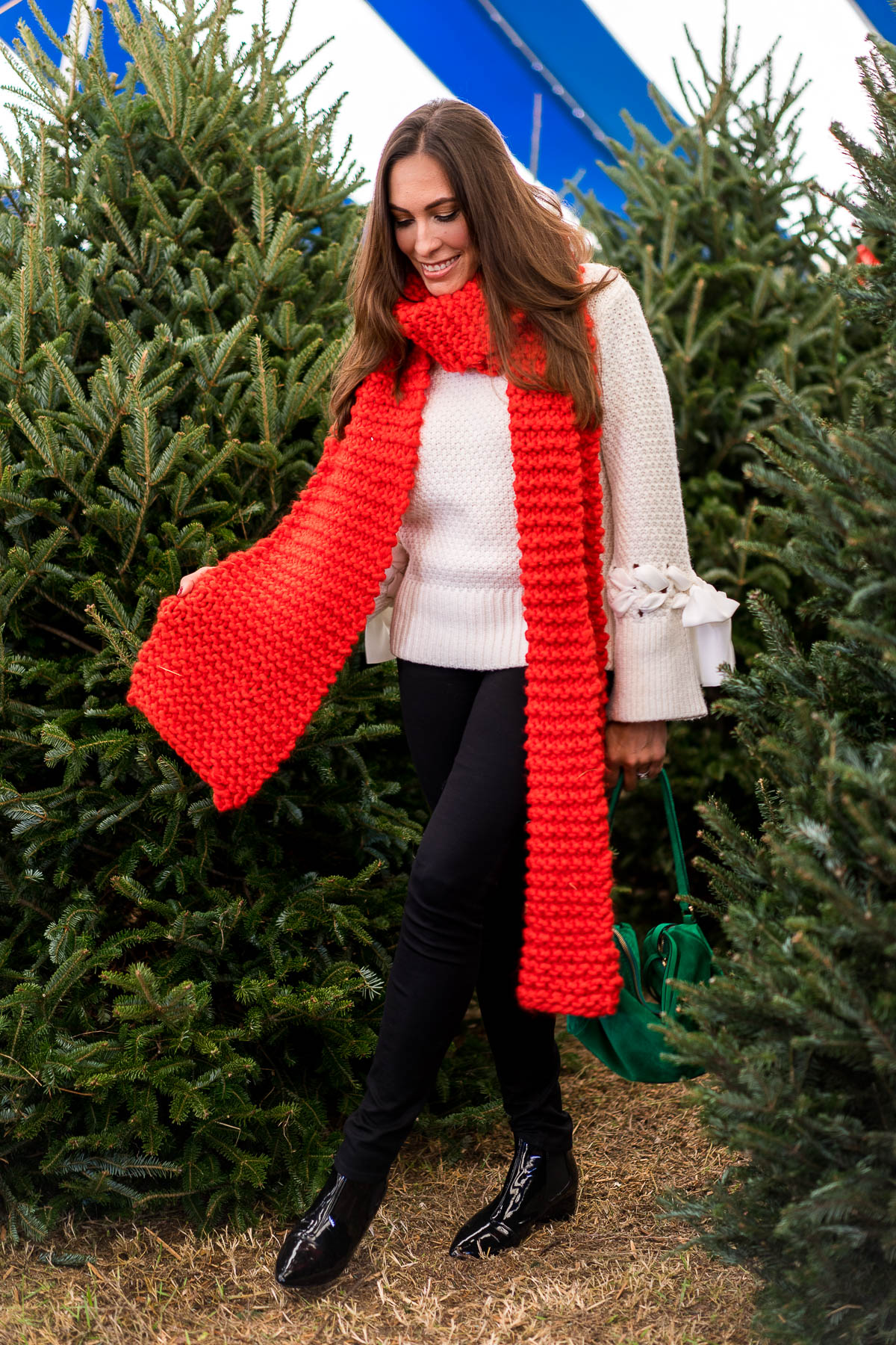 Amanda from A Glam Lifestyle fashion blogger wears oversized red scarf with cream colored sweater to visit Christmas Trees Pompano