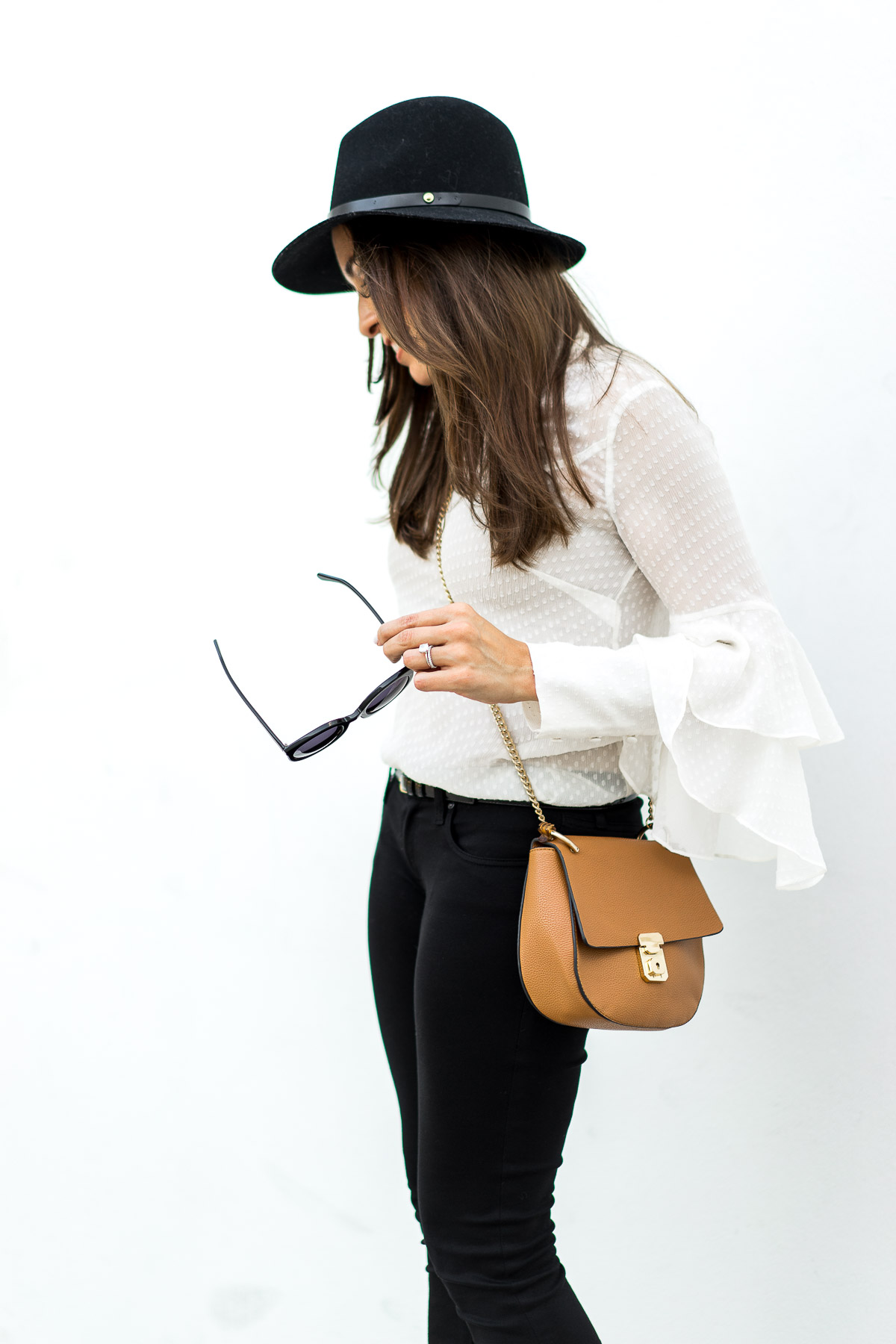 Fashion blogger Amanda who writes A Glam Lifestyle wears Olivia Palermo x Chelsea28 sheer white blouse with Chloe Drew bag dupe and black AG Jeans leggings