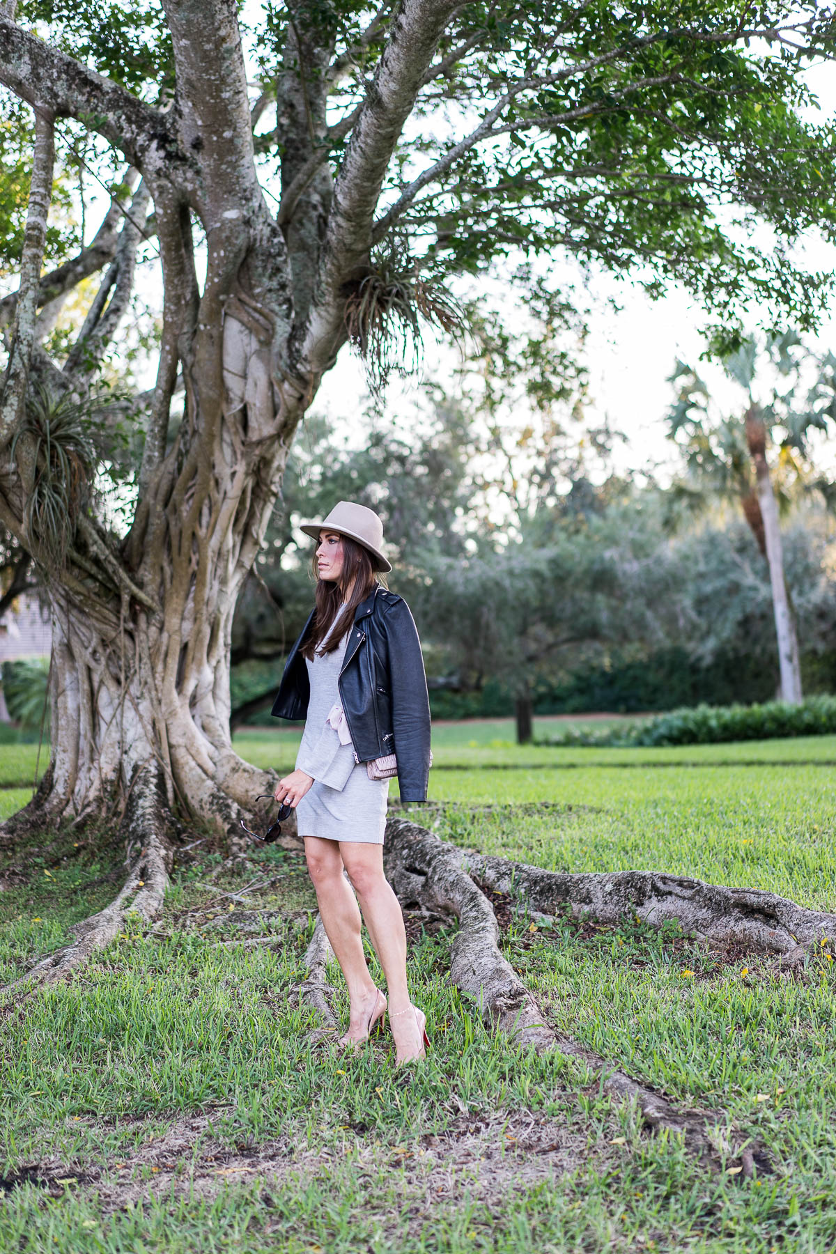 Fashion blogger Amanda from A Glam Lifestyle wears Maje black leather moto jacket and Club Monaco grey sweater dress with Christian Louboutin Pigalle nude pumps