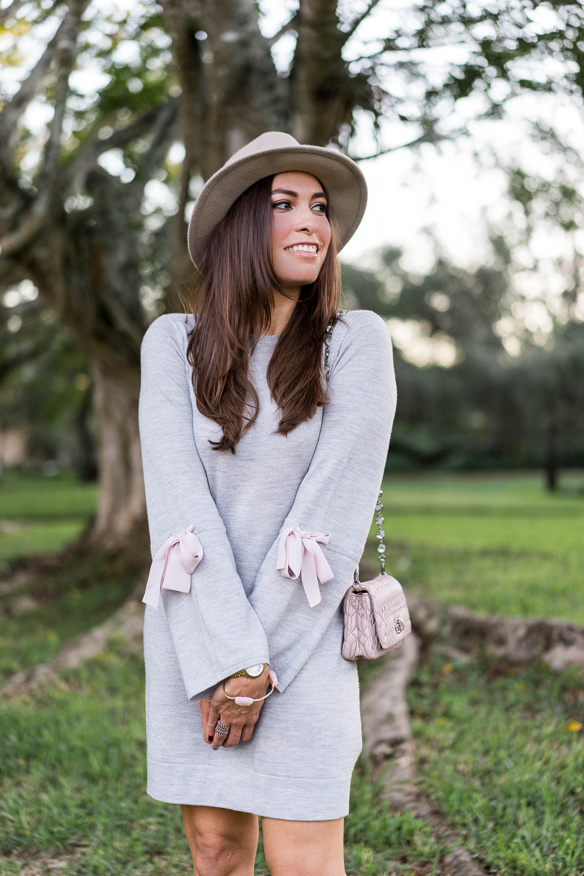 A Glam Lifestyle fashion blogger wears Club Monaco Sohrab sweater dress with pink bow details and Miu Miu Nappa Crystal blush pink bag