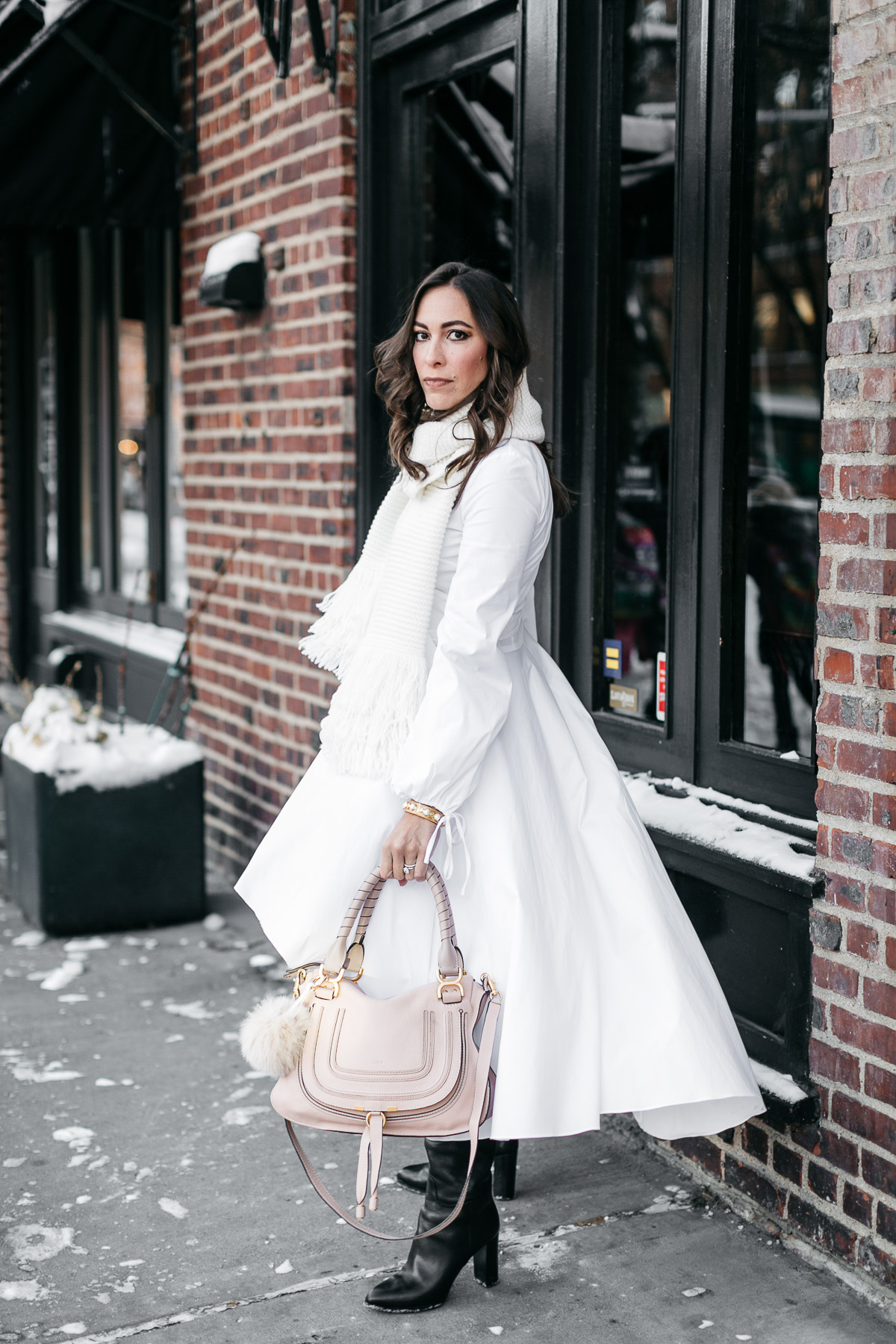 Amanda from A Glam Lifestyle blog wears Carolina Constas Lena white shirt dress during NYFW Spring 2017 shows carrying her Chloe Marcie bag and accessorized with MGemi Pendolo black boots and Club Monaco Juki white fringed scarf