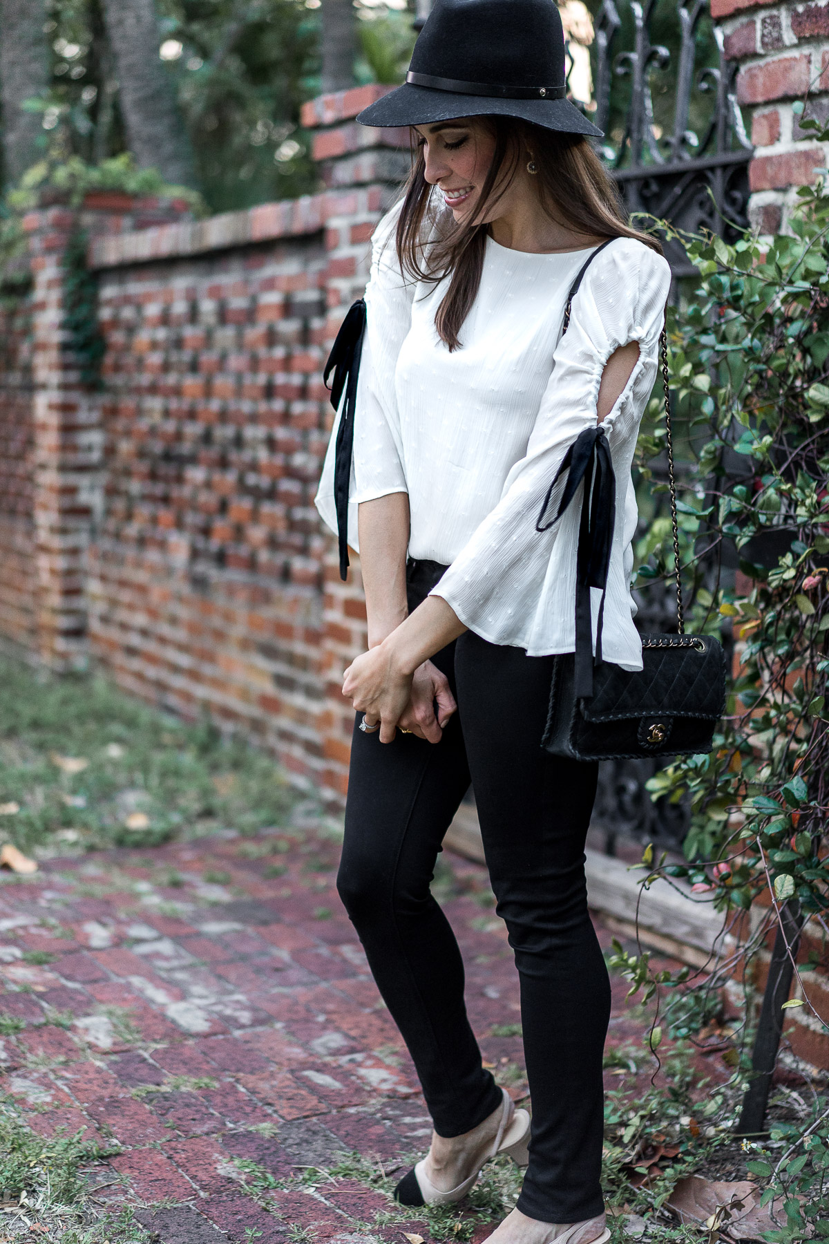 Pretty Club Monaco bell sleeve top with black ribbon tie styled by South Florida blogger Amanda of A Glam Lifestyle worn with Chanel suede bag and black AG Leggings jeans