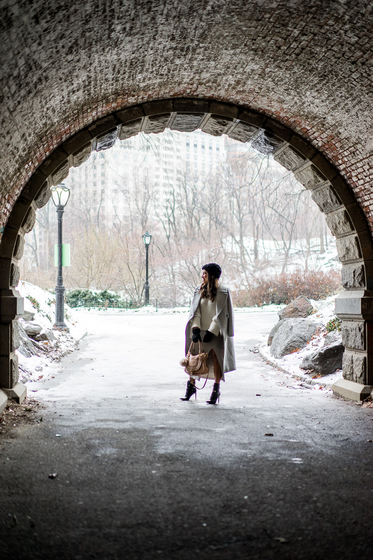 Fashion blogger Amanda visits Central Park tunnel during NYFW wearing BCBGeneration grey midi sweater skirt and carrying Chloe Marcie bag while it snows