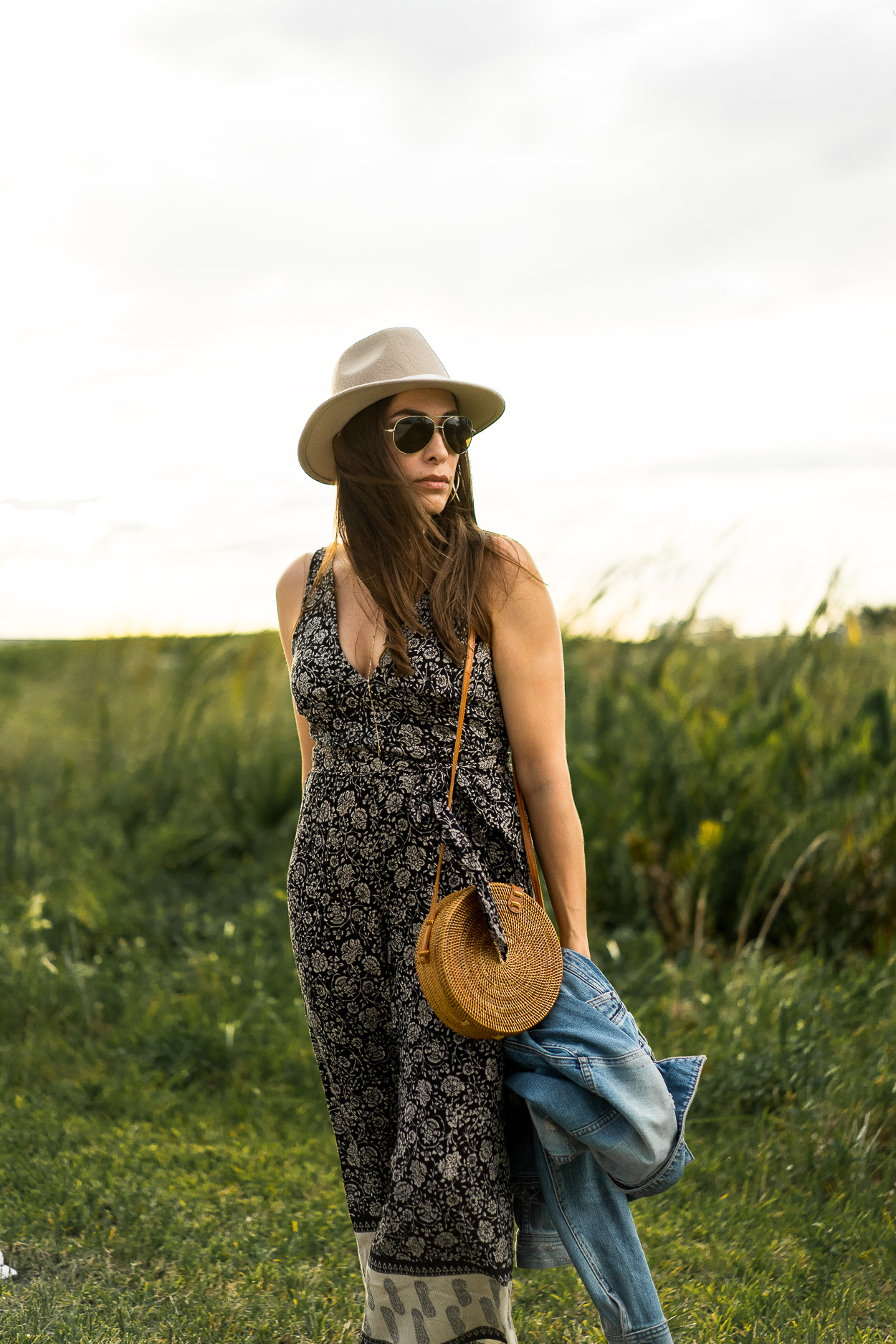 South Florida fashion blogger Amanda of A Glam Lifestyle wears boho style jumpsuit by Amuse Society with chic Summer accessories including round basket bag and classic denim jacket