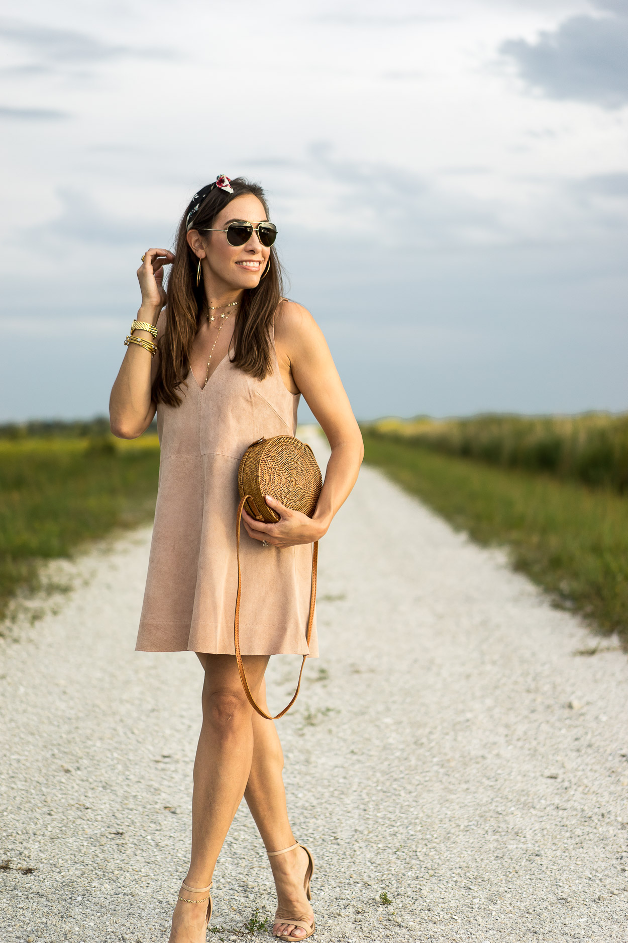 Blogger Amanda from AGlamLifestyle shows how to wear a suede dress in Summer with round basket bag and floral bandana