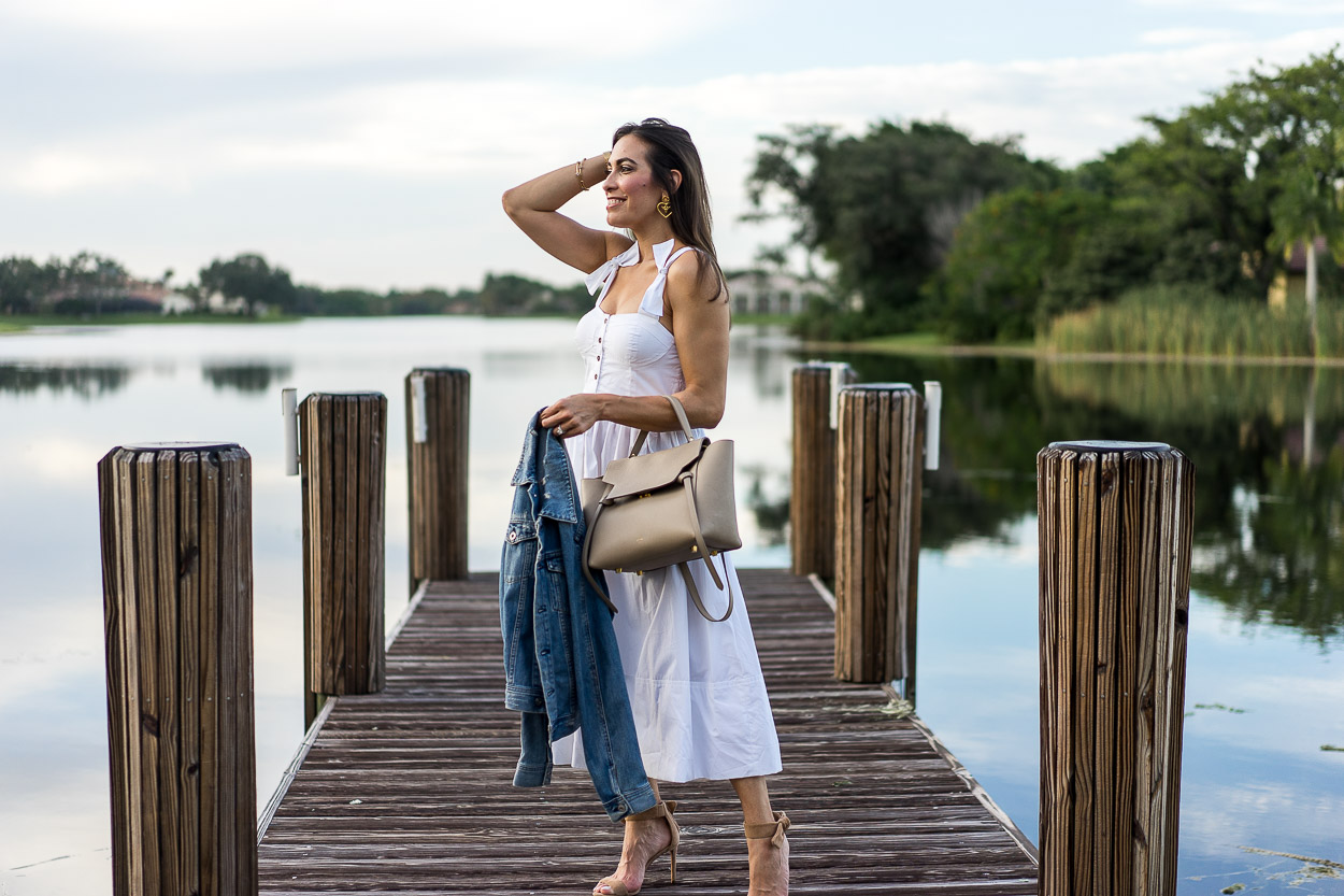 Dress up at the lake in a Summer white dress by Chicwish with a classic denim jacket and neutral accessories