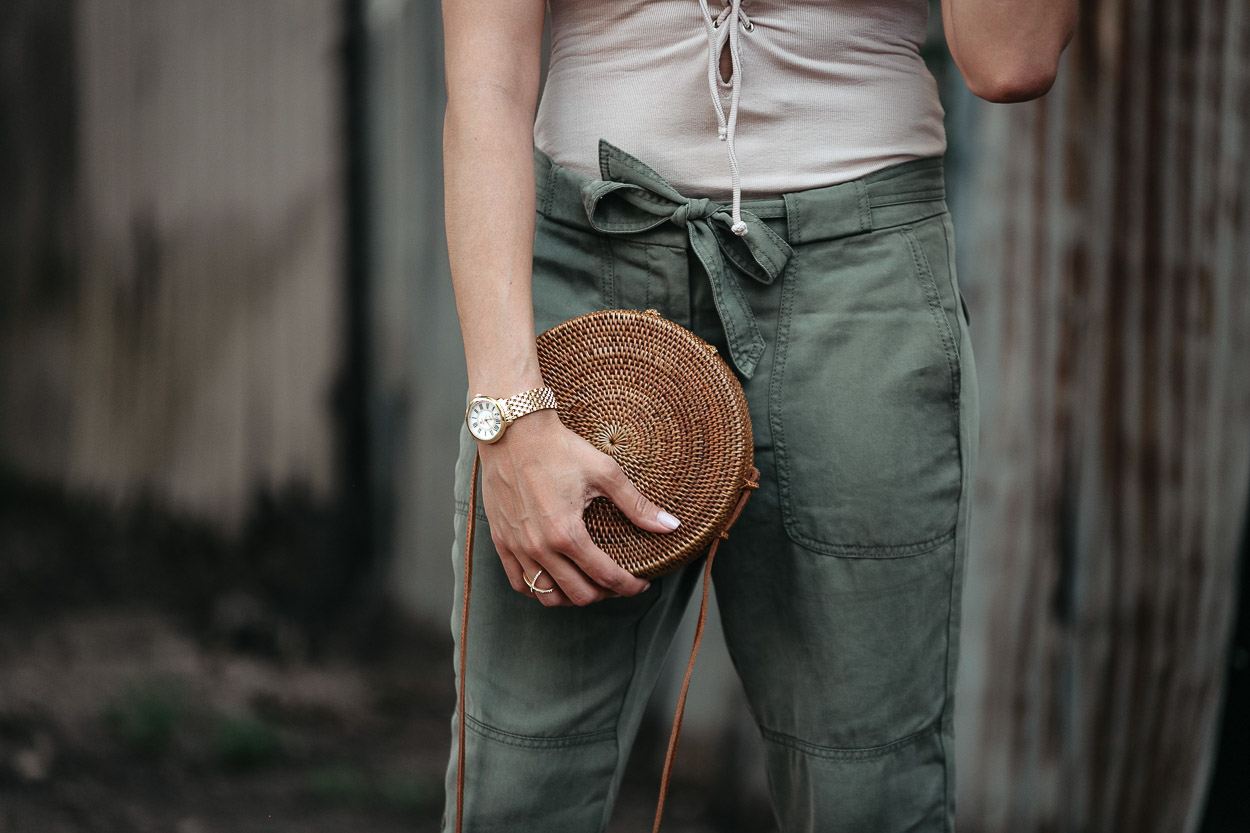 A round basket bag perfectly compliments tie waist cargo pants and a lace up bodysuit by Tularosa