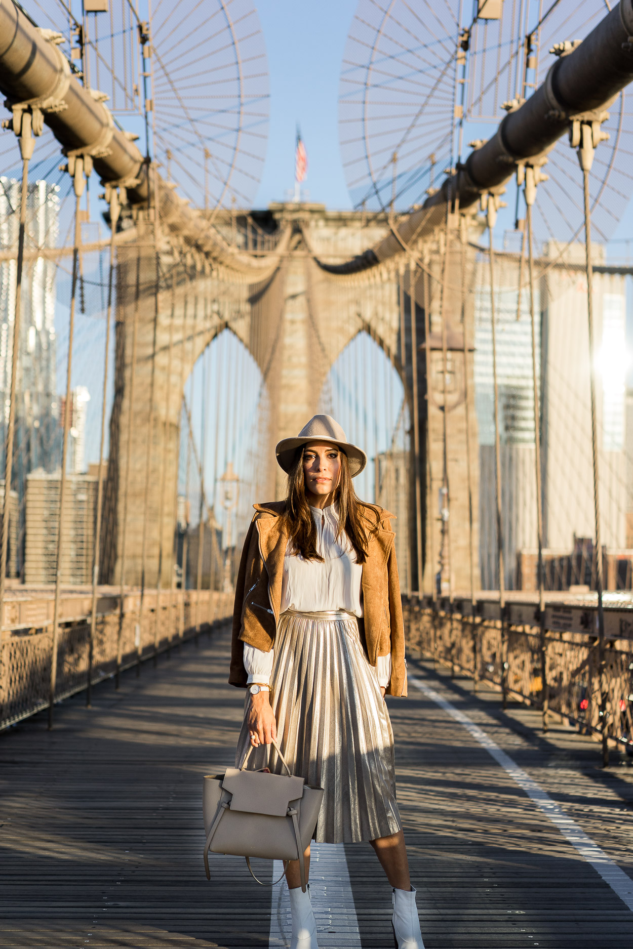 A metallic pleated skirt is trending for Fall and blogger A Glam Lifestyle shares how she styles hers with pretty neutrals like a cream top by Aritzia with a Lulus camel suede jacket and Topshop white ankle booties