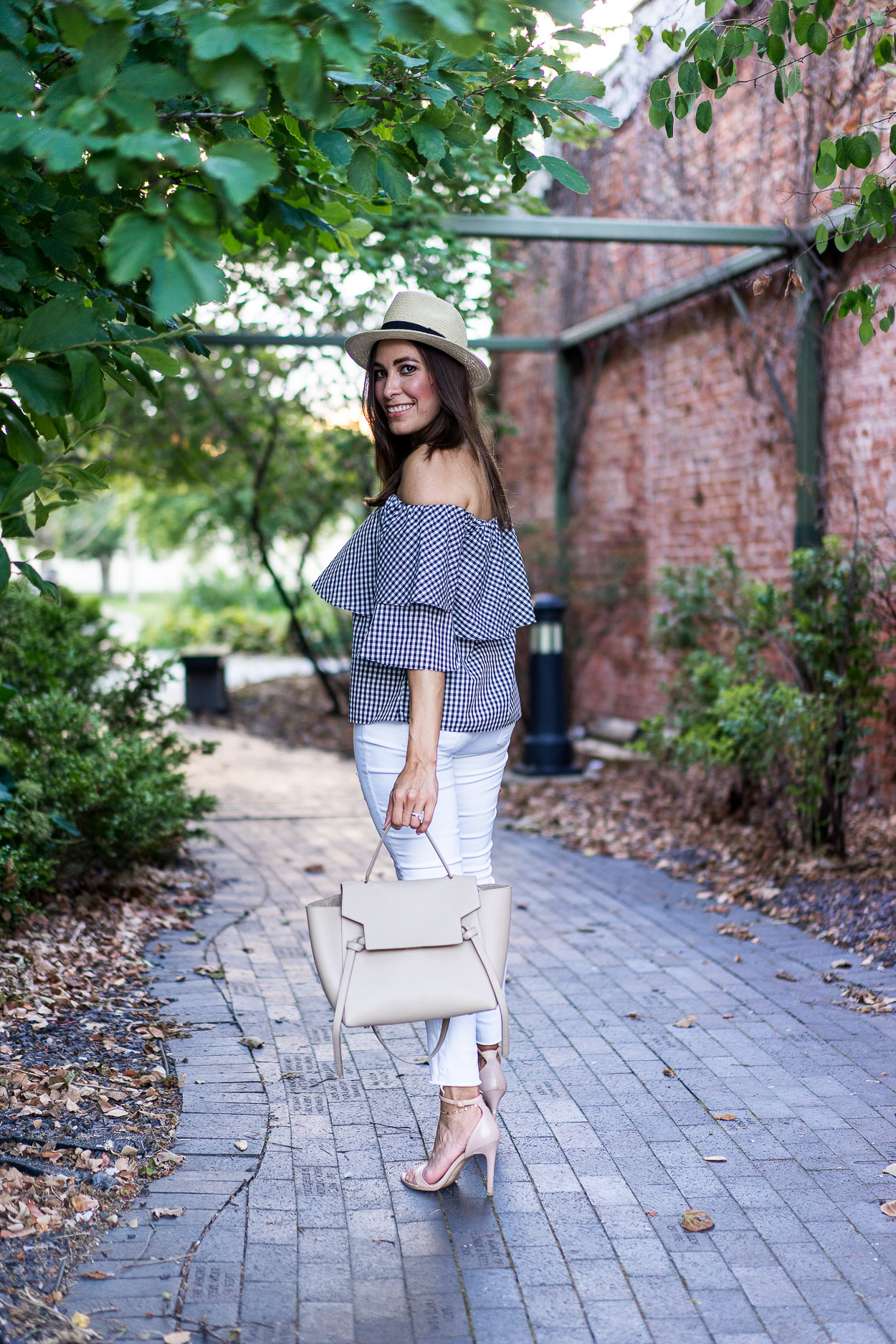 A Glam Lifestyle blogger wears Wayf gingham top with AG jeans white legging jeans and nude Steve Madden sandals and nude Celine Belt bag