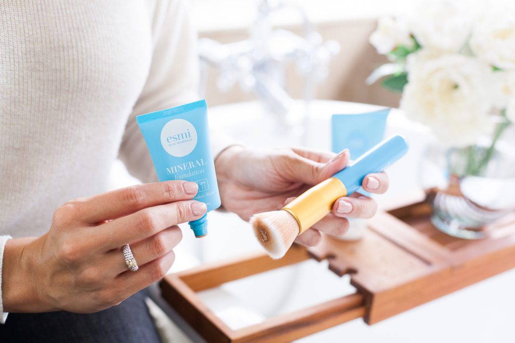 woman adding esmi mineral foundation on a brush 