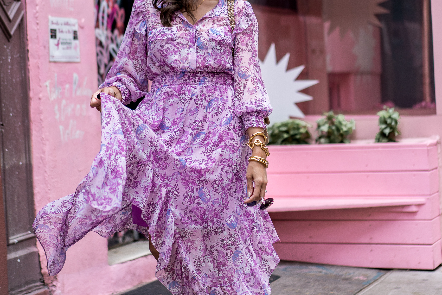 woman standing by a heart wall mural and wearing a purple dress, Julie Vos Catalina Hinge Bangle and Julie Vos Savannah Demi Link Bracelet.