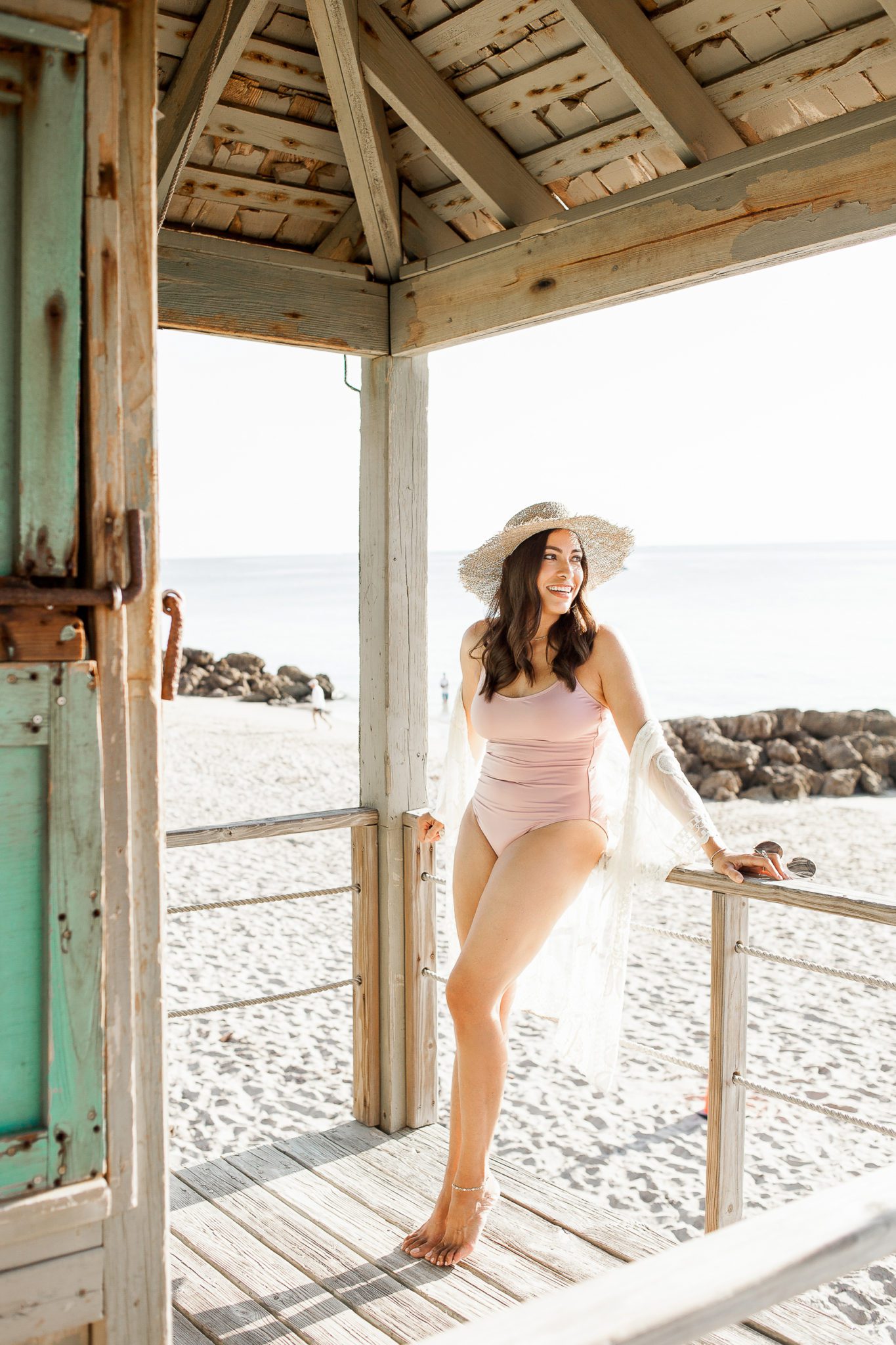 A Glam Lifestyle Blogger Amanda Champion wearing a pink swimsuit at the beach